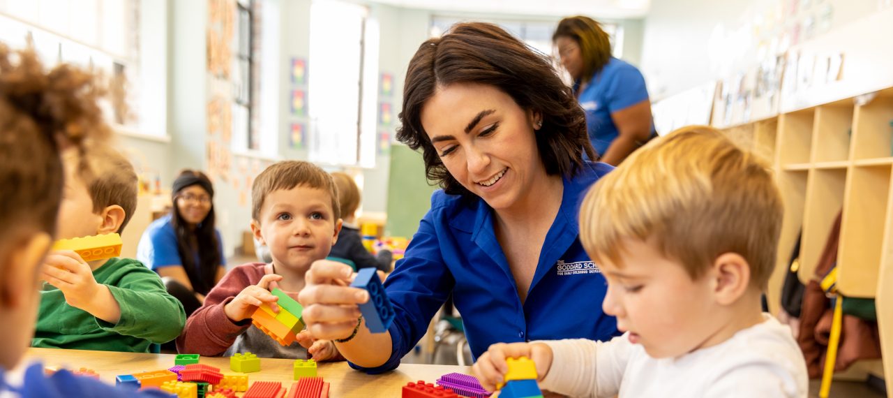 Goddard School franchisee playing with children and building blocks at preschool classroom table
