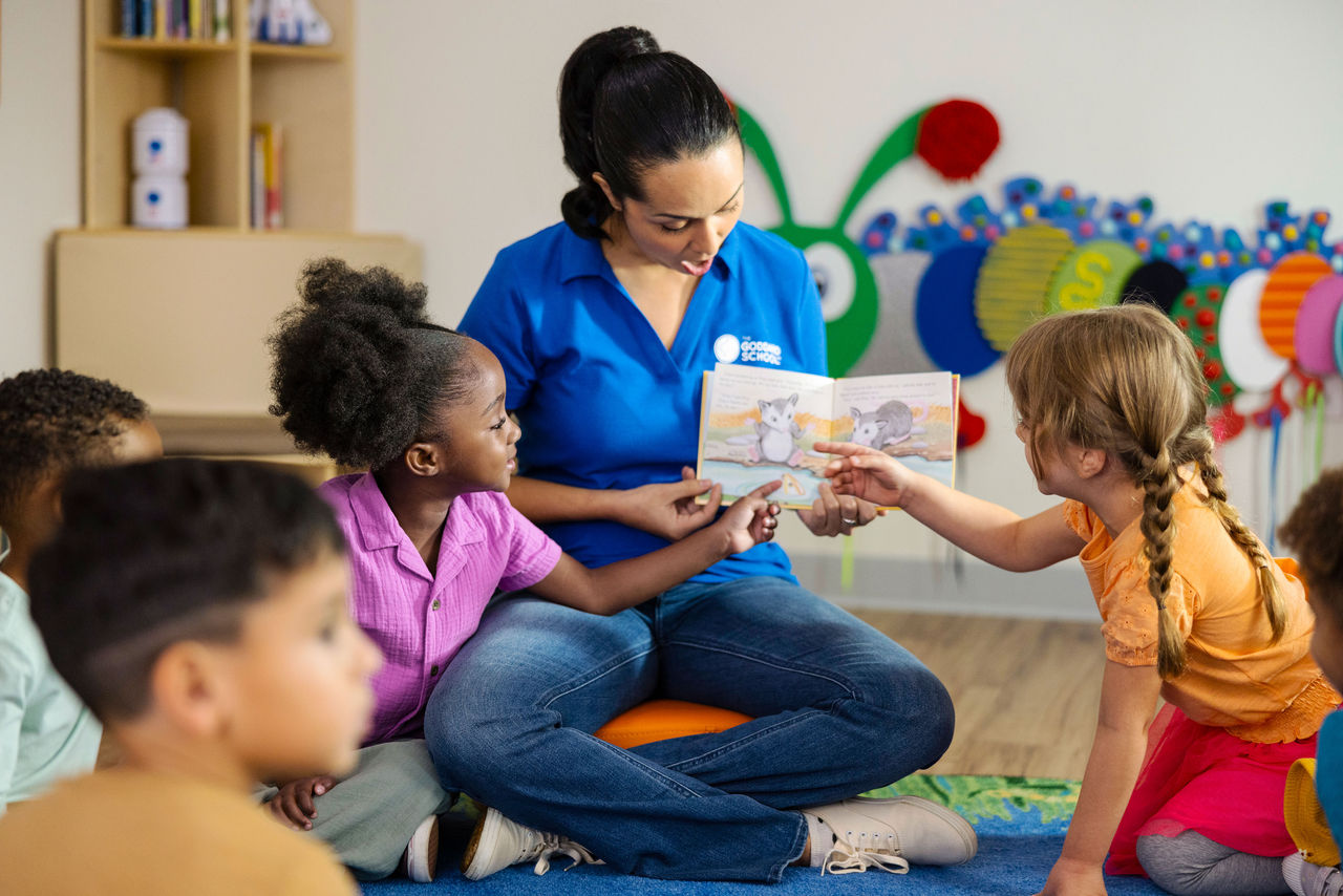 Teacher reading a book to children in circle time at a Goddard School